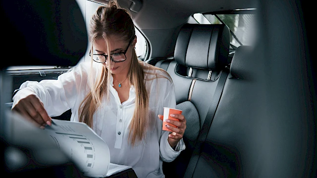 Nő papírokat olvas a gépjármű hátsó ülésén