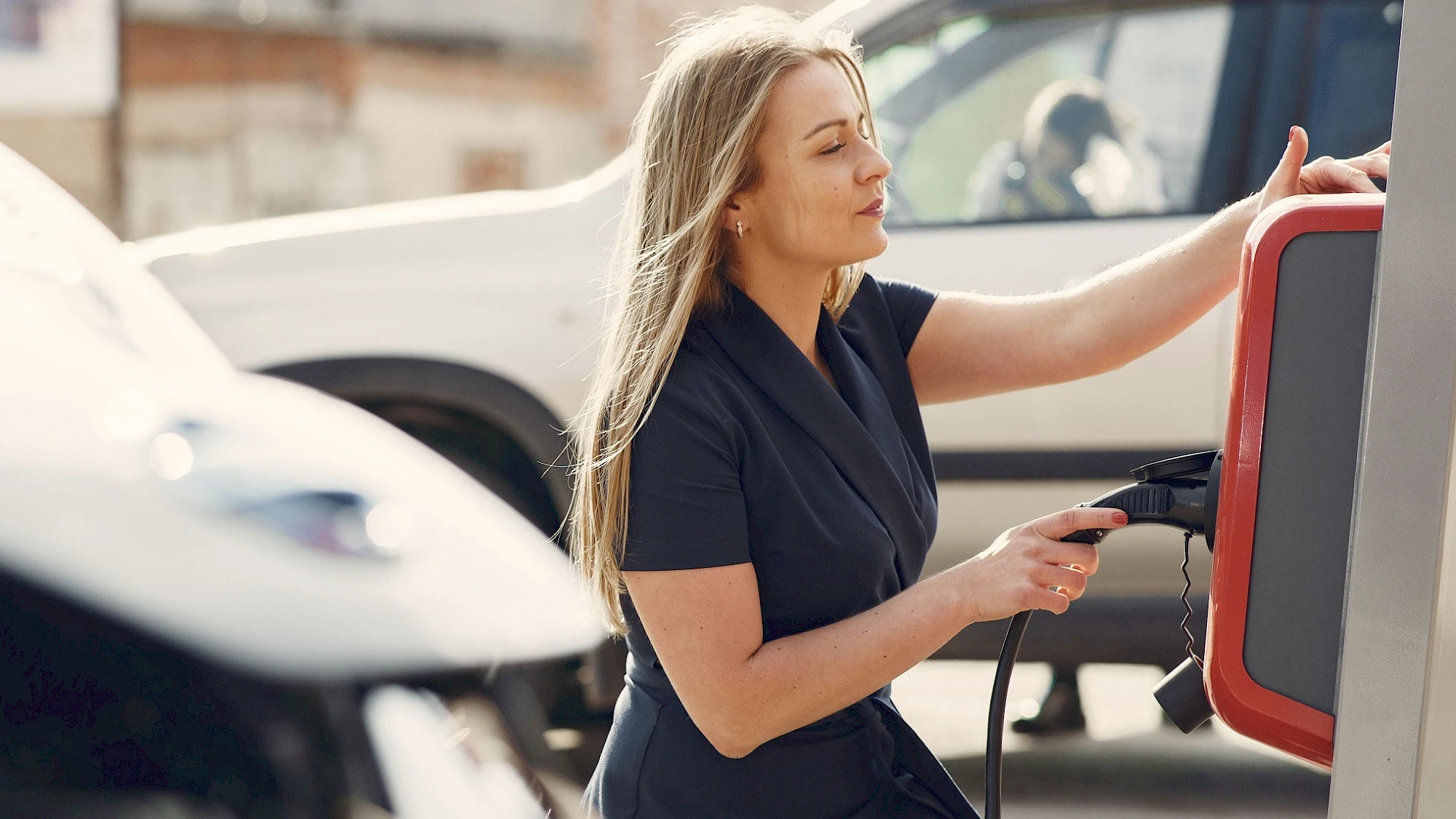 Nő töltőre helyezi az elektromos autót